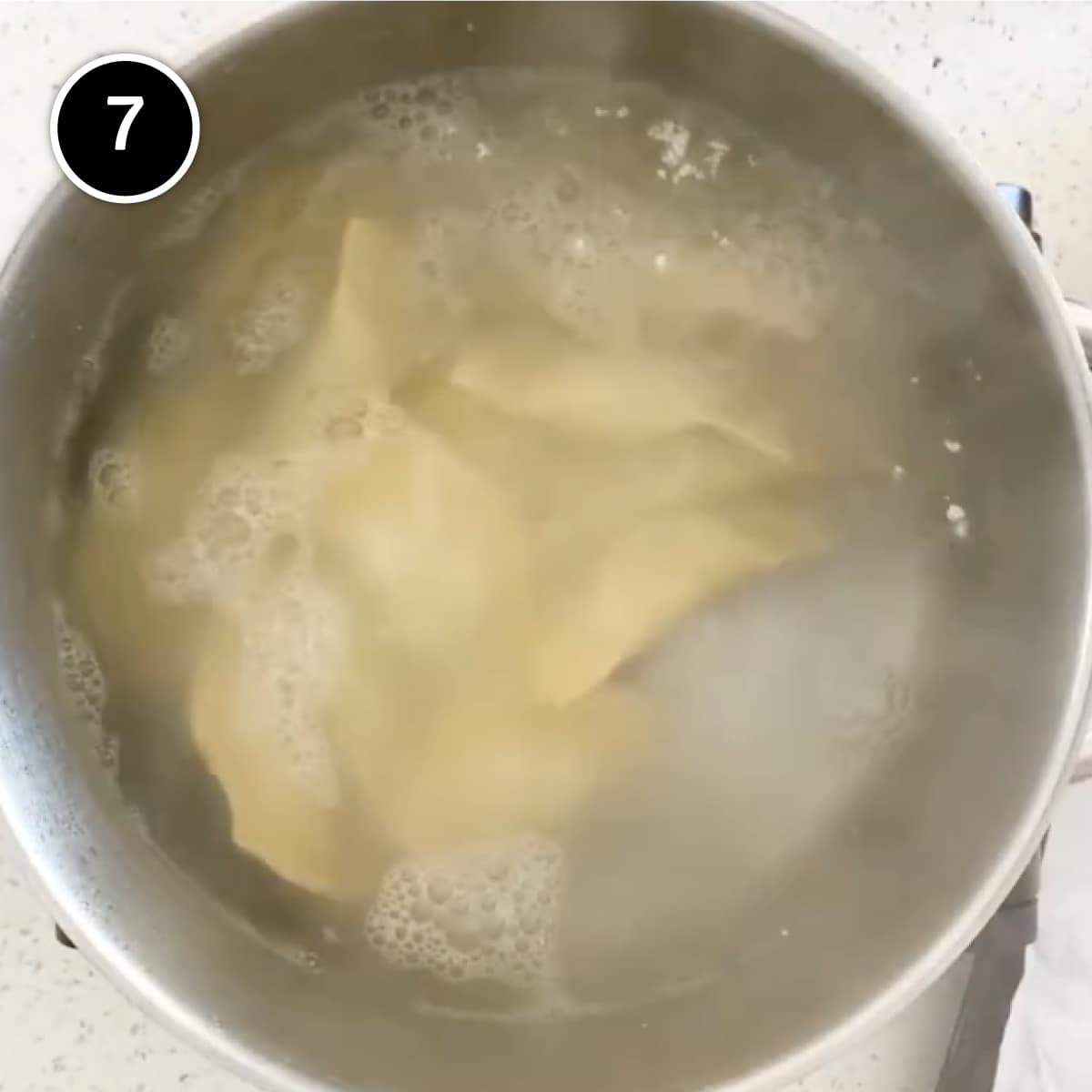 Mezzelune pasta cooking in a pan of water.
