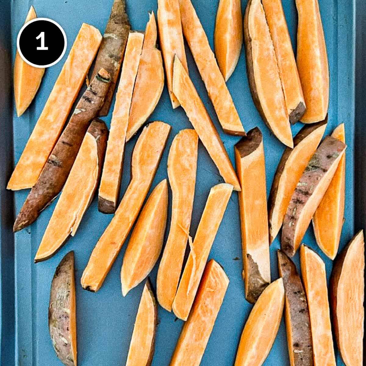 Raw sweet potato wedges on a sheet pan.