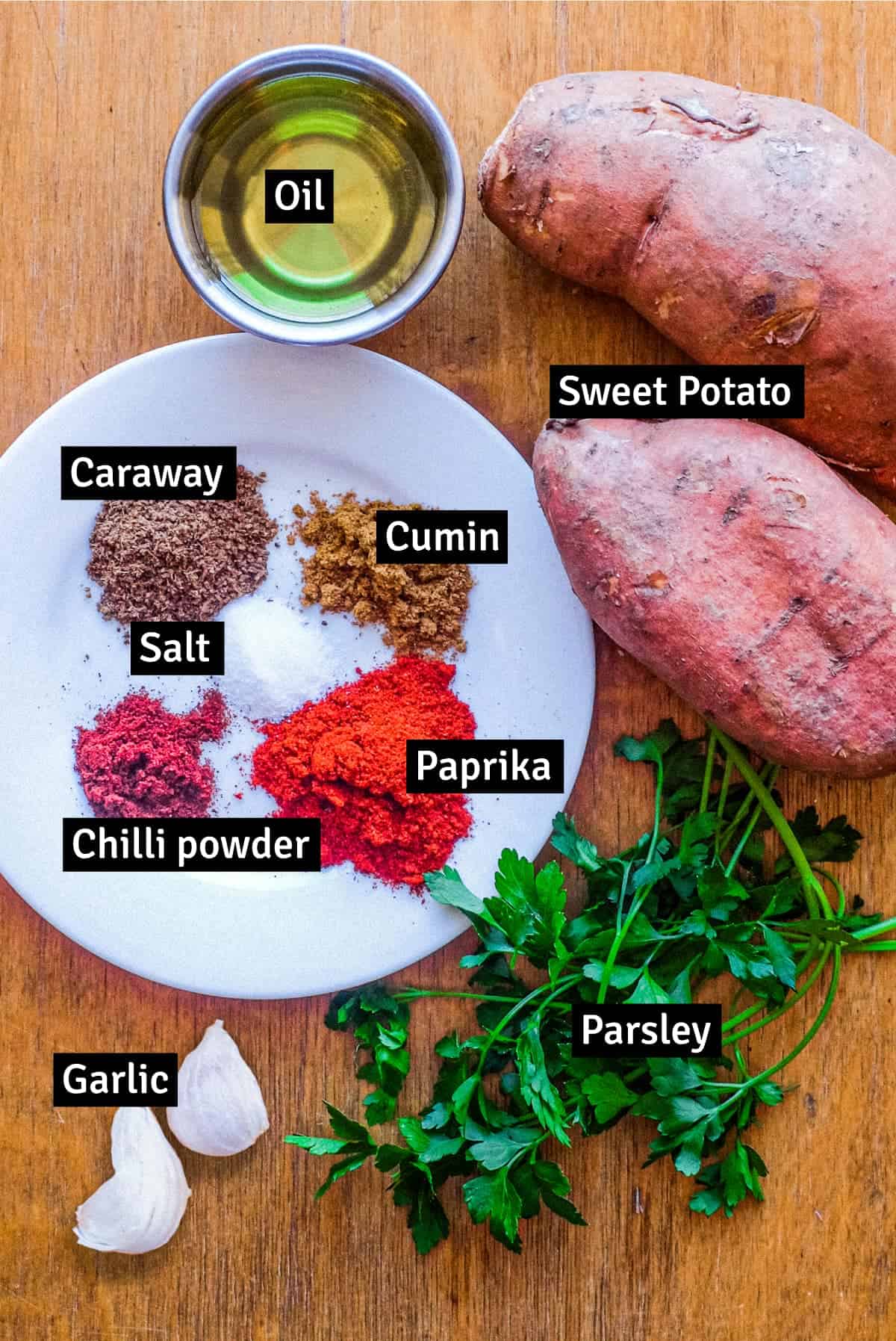 The ingredients for Pilpelchuma with sweet potatoes: sweet potatoes, cumin, caraway, chilli powder, salt, paprika, oil garlic and parsley.