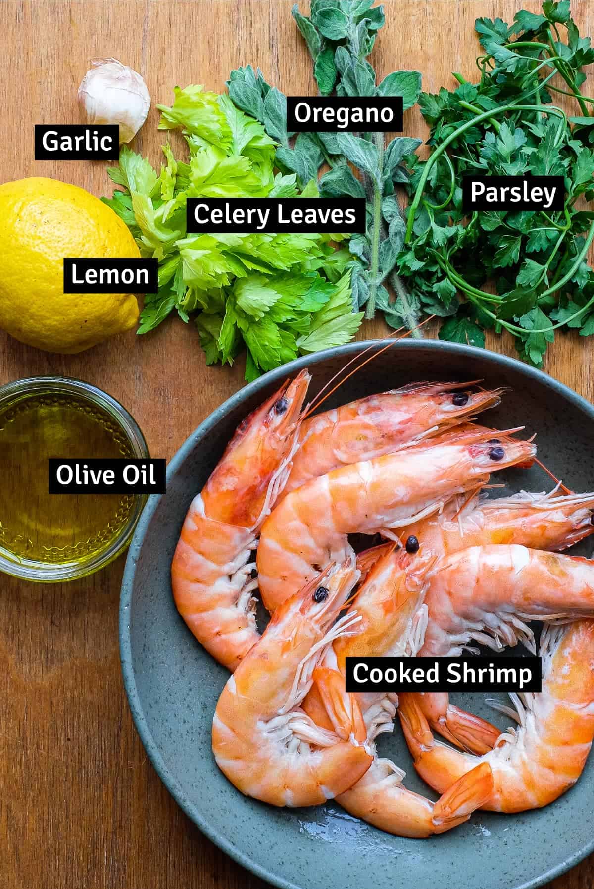 The ingredients for Italian Salmoriglio sauce with shrimp: herbs, lemon, oil, garlic and shrimp.