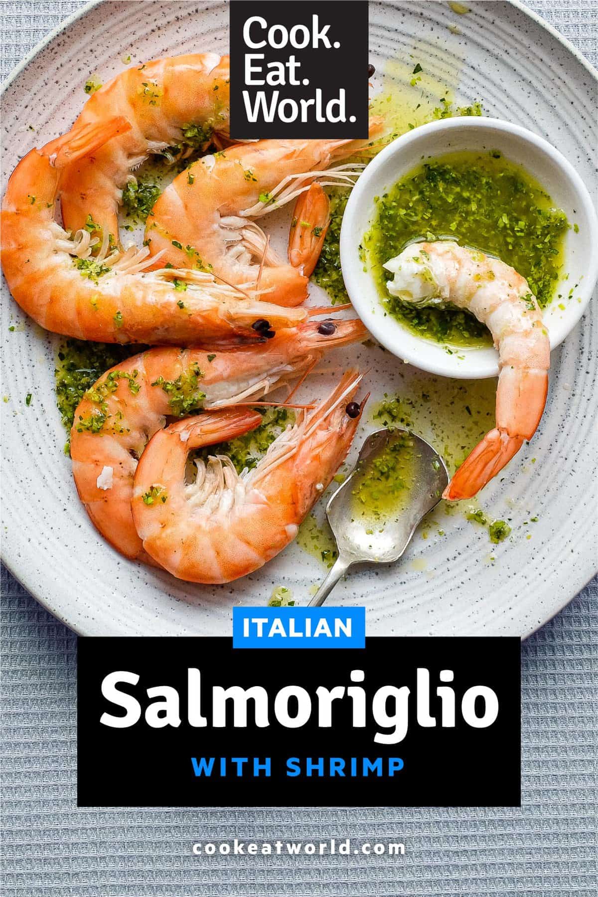 A platter of King Prawns with a small bowl of Italian Salmoriglio sauce, a herb and lemon dressing. A small spoon sits in the bowl.