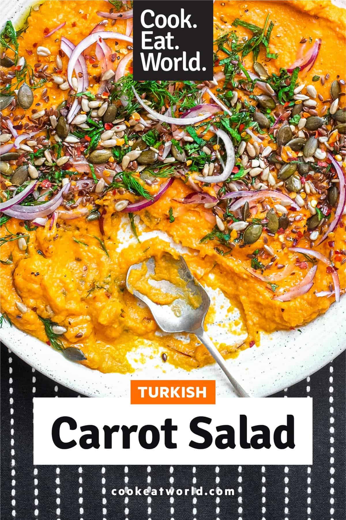 A platter of Turkish carrot salad scattered with herbs, seeds and red onion