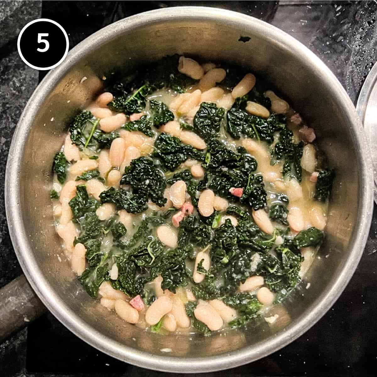 Adding Cavolo Nero cabbage to a small pan of Tuscan beans