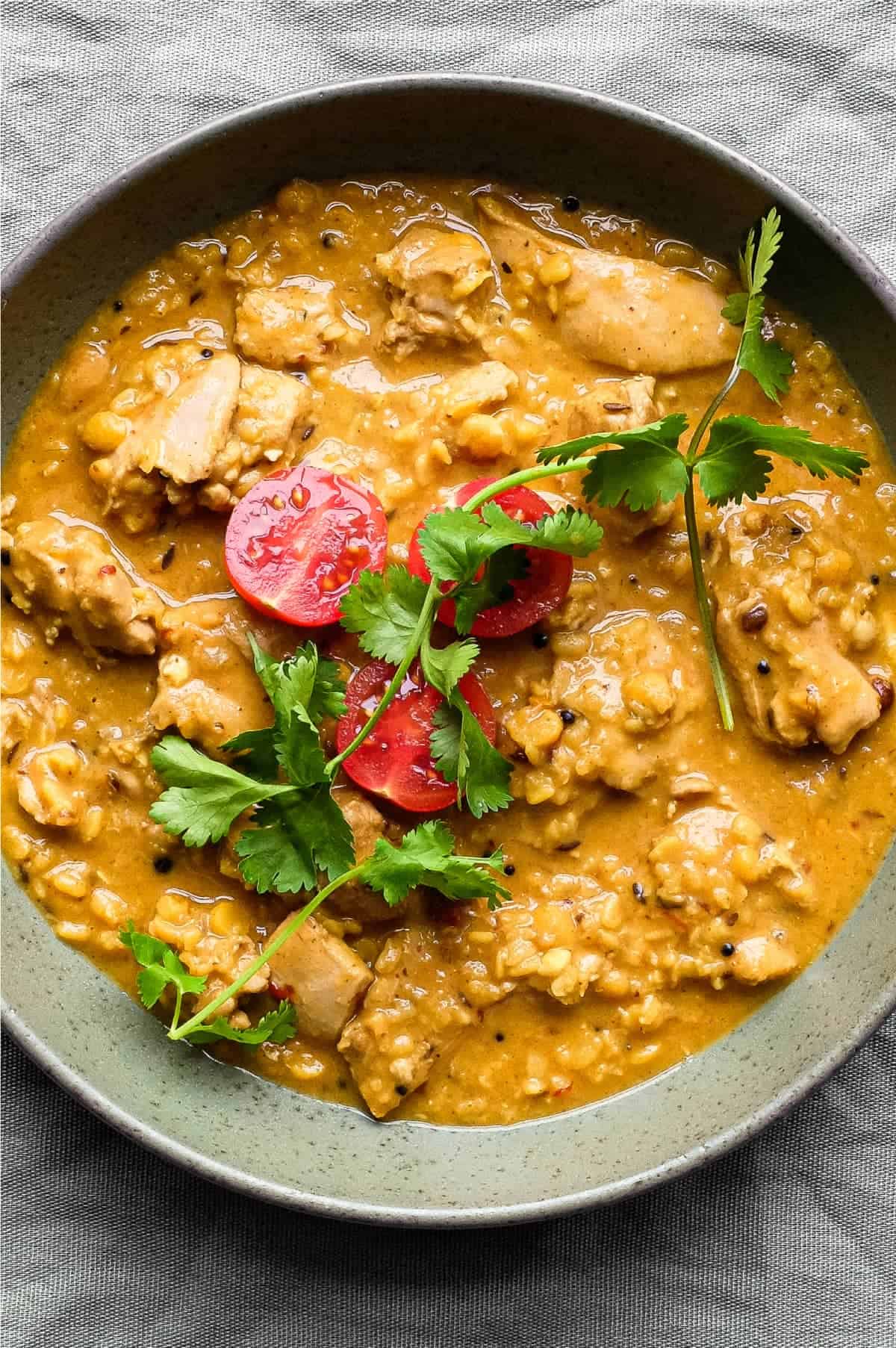 A bowl of lentil curry garnished with some cherry tomatoes and a little cilantro