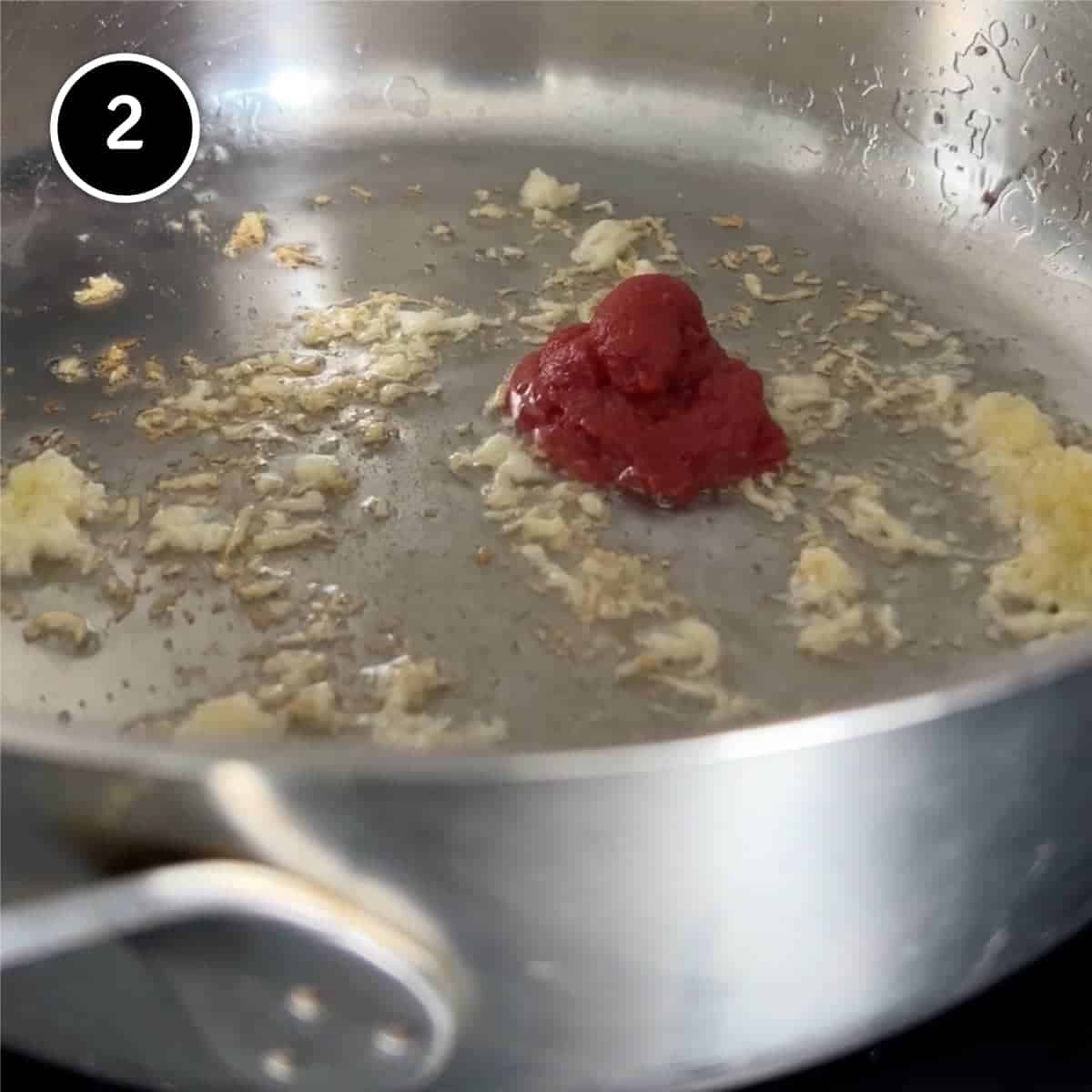 Adding tomato to a pan of frying garlic