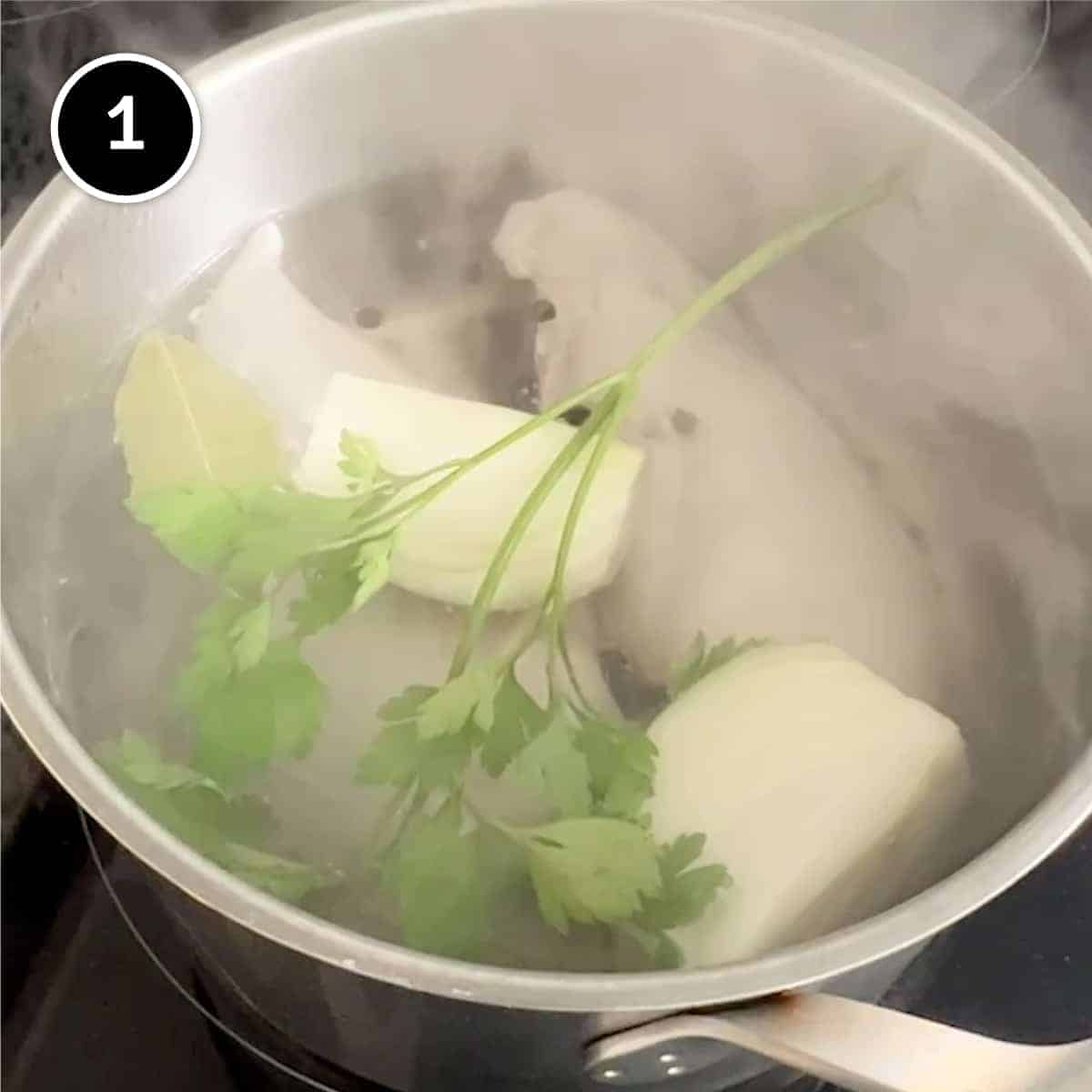 poaching chicken breasts in a pan with onion, parsley, bay leaf and peppercorns