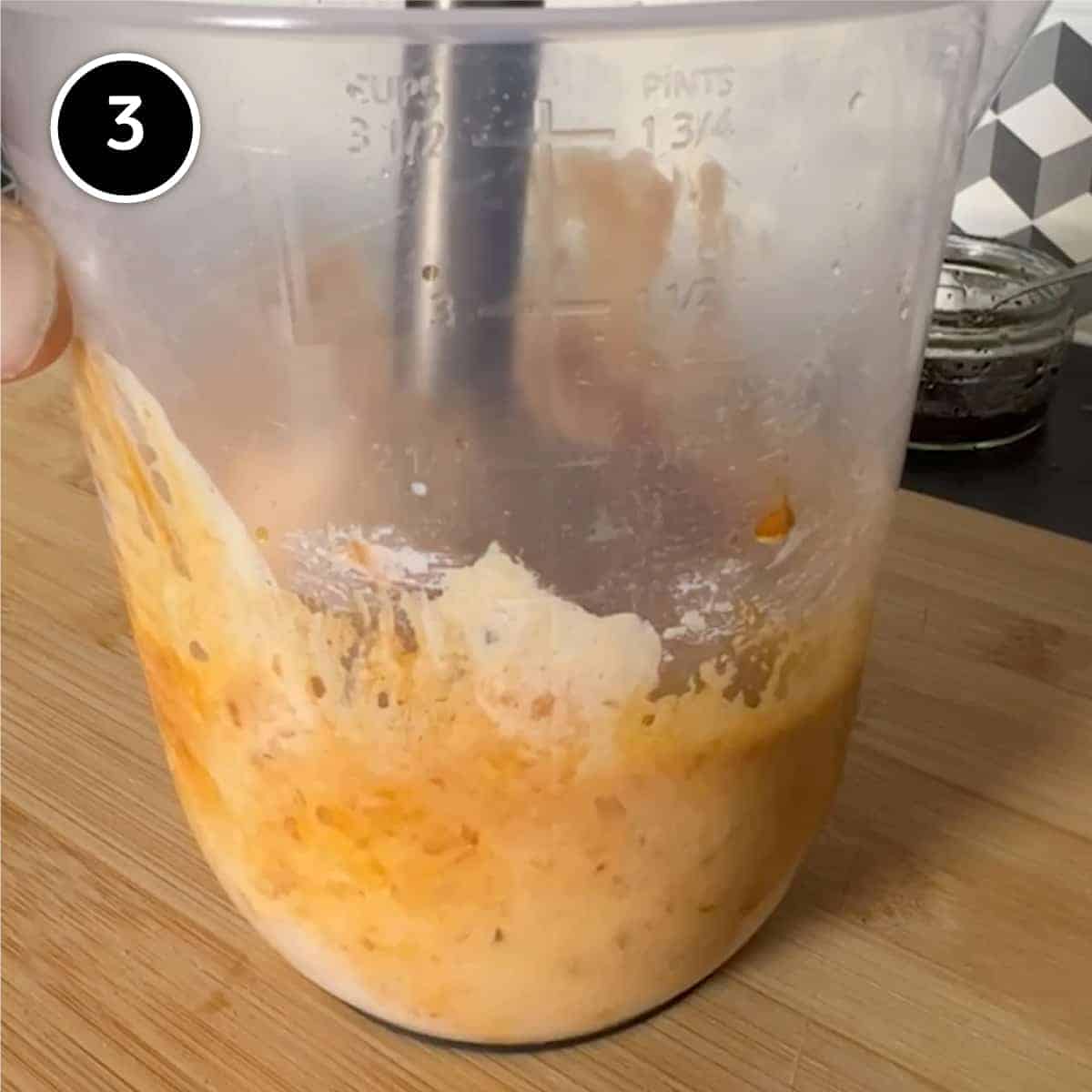 blending Circassian walnut sauce with a stick blender in a plastic jug