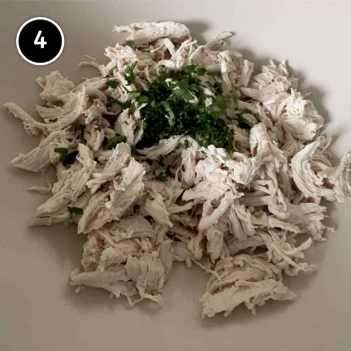 Shredded chicken in a bowl with parsley on top
