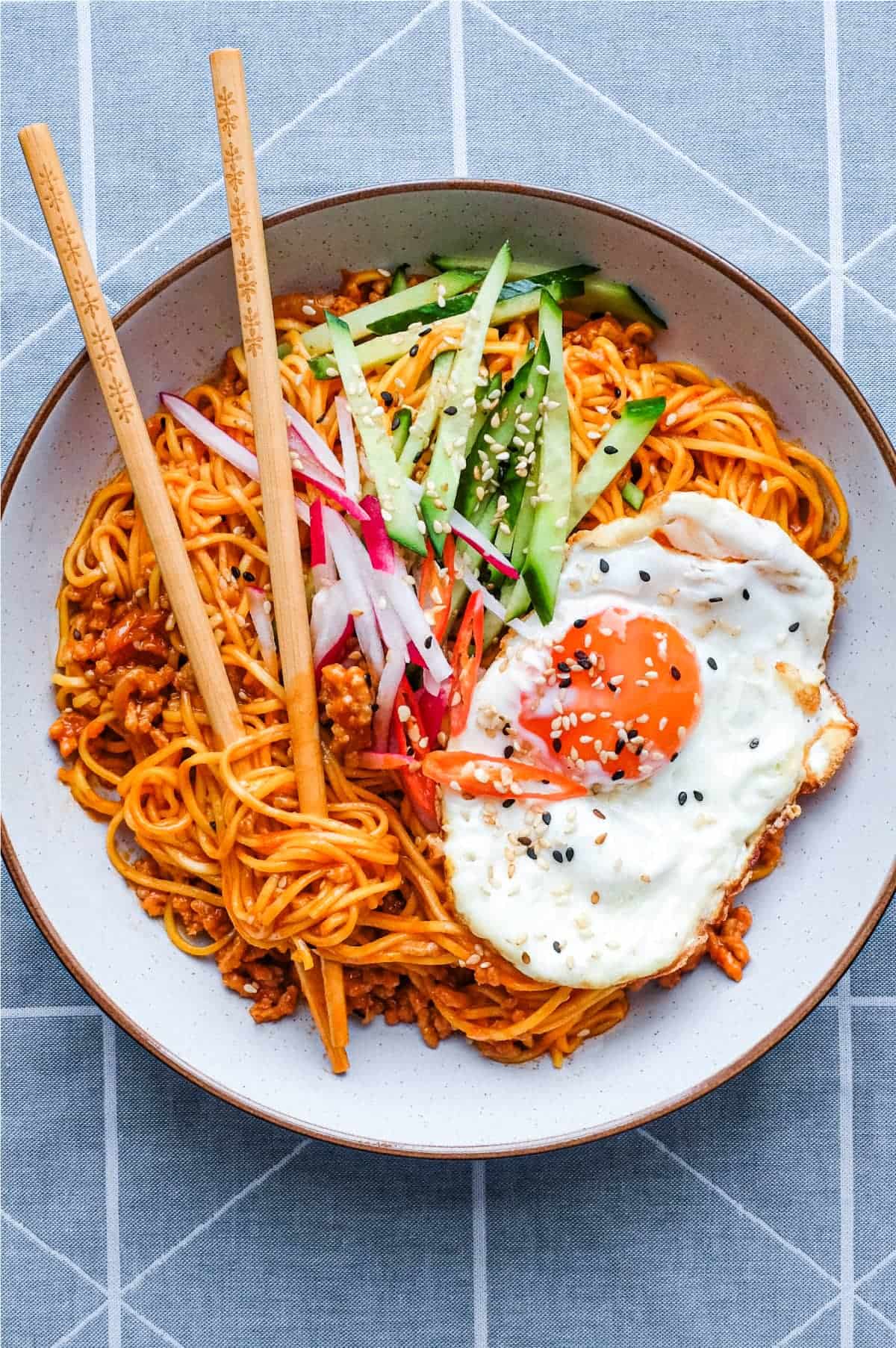 A bowl of Korean Gochujang Noodles with Pork with a fried egg on top