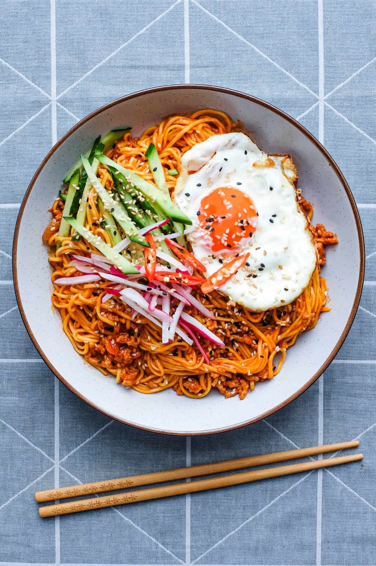 A bowl of Korean Gochujang Noodles with Pork with a fried egg on top