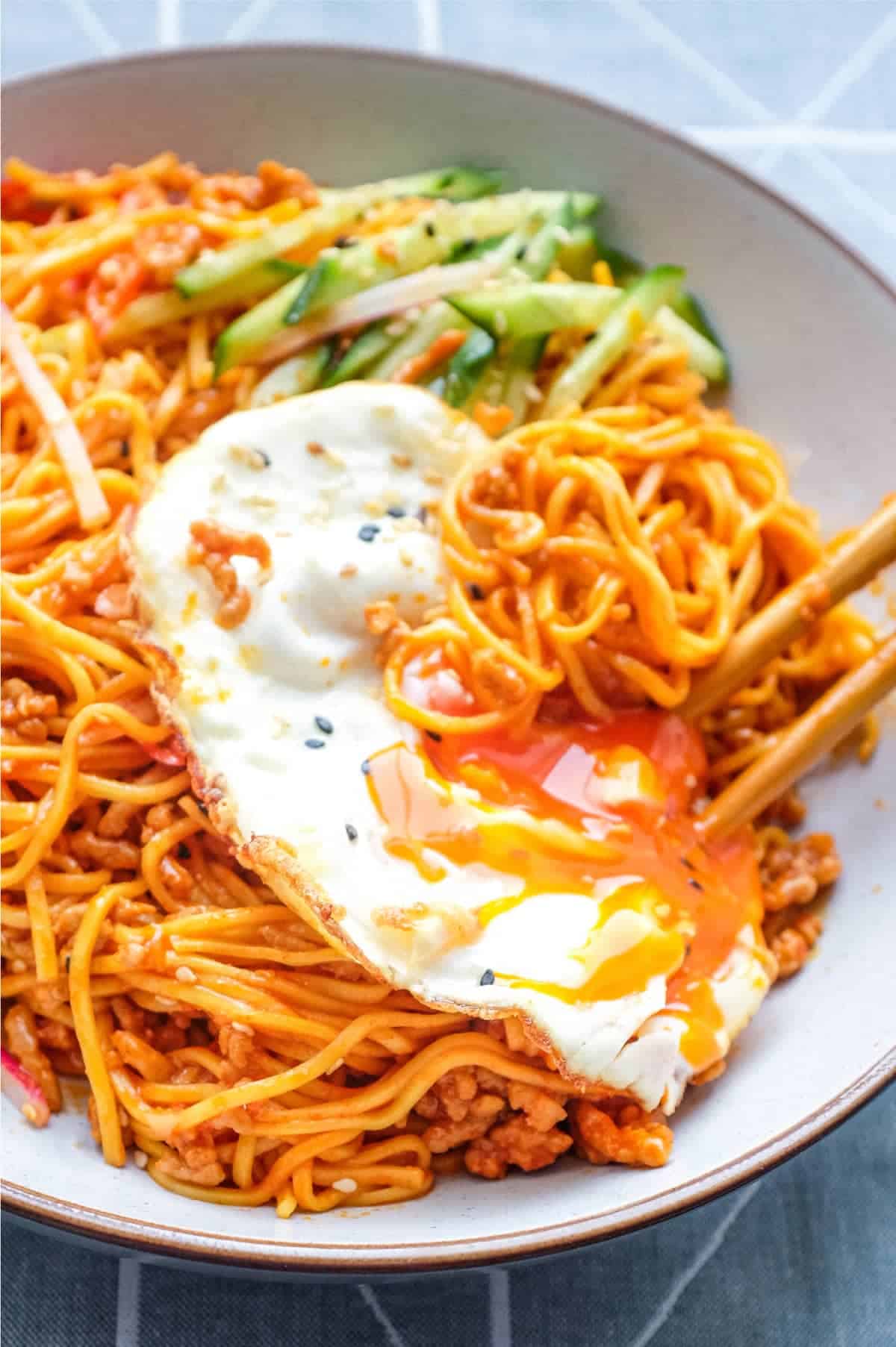 A bowl of Korean Gochujang Noodles with Pork with a fried egg on top