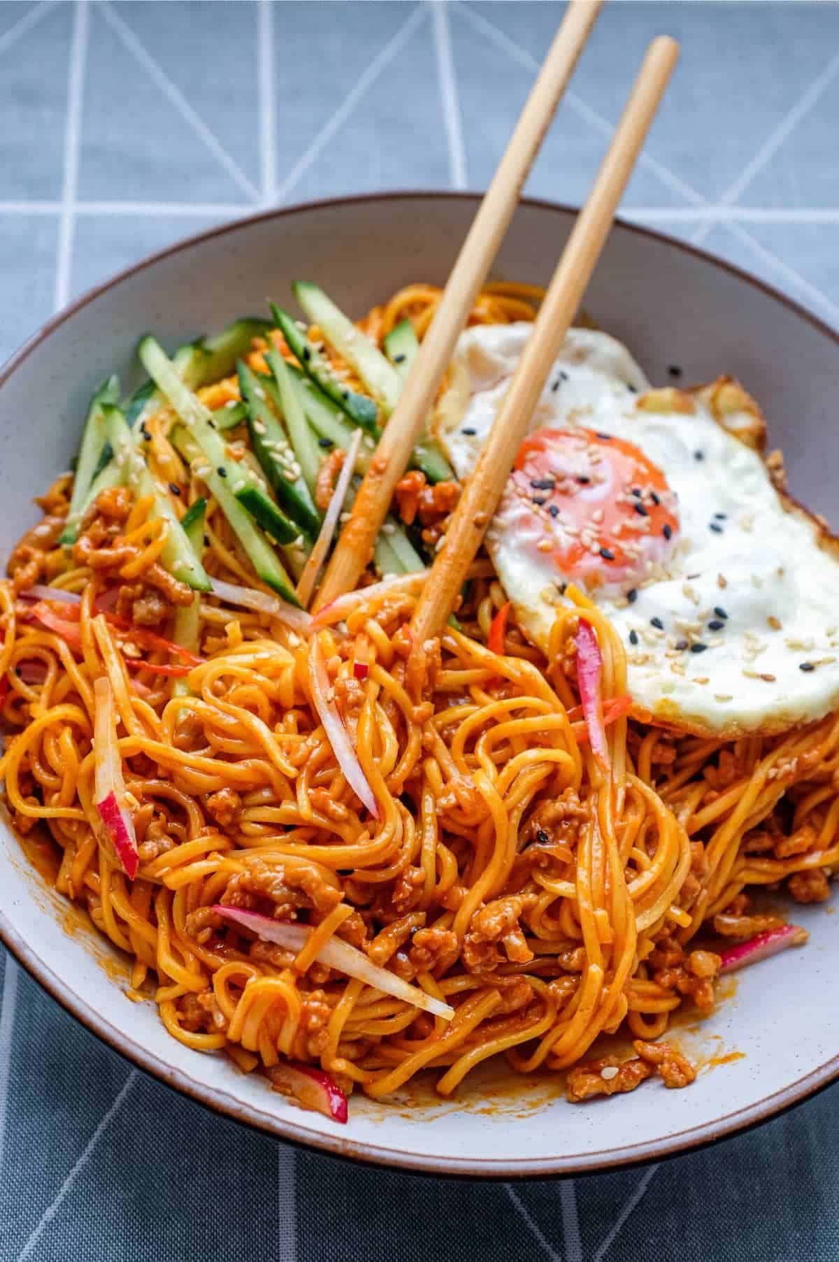 A bowl of Korean Gochujang Noodles with Pork with a fried egg on top