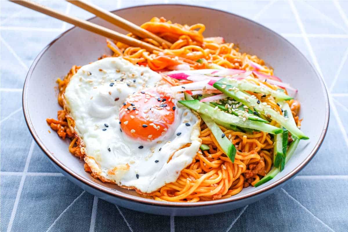 A bowl of Korean Gochujang Noodles with Pork with a fried egg on top