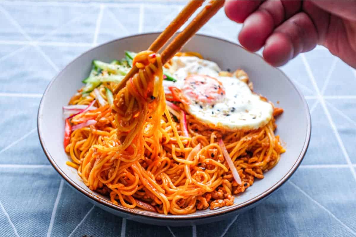 A bowl of Korean Gochujang Noodles with Pork with a fried egg on top