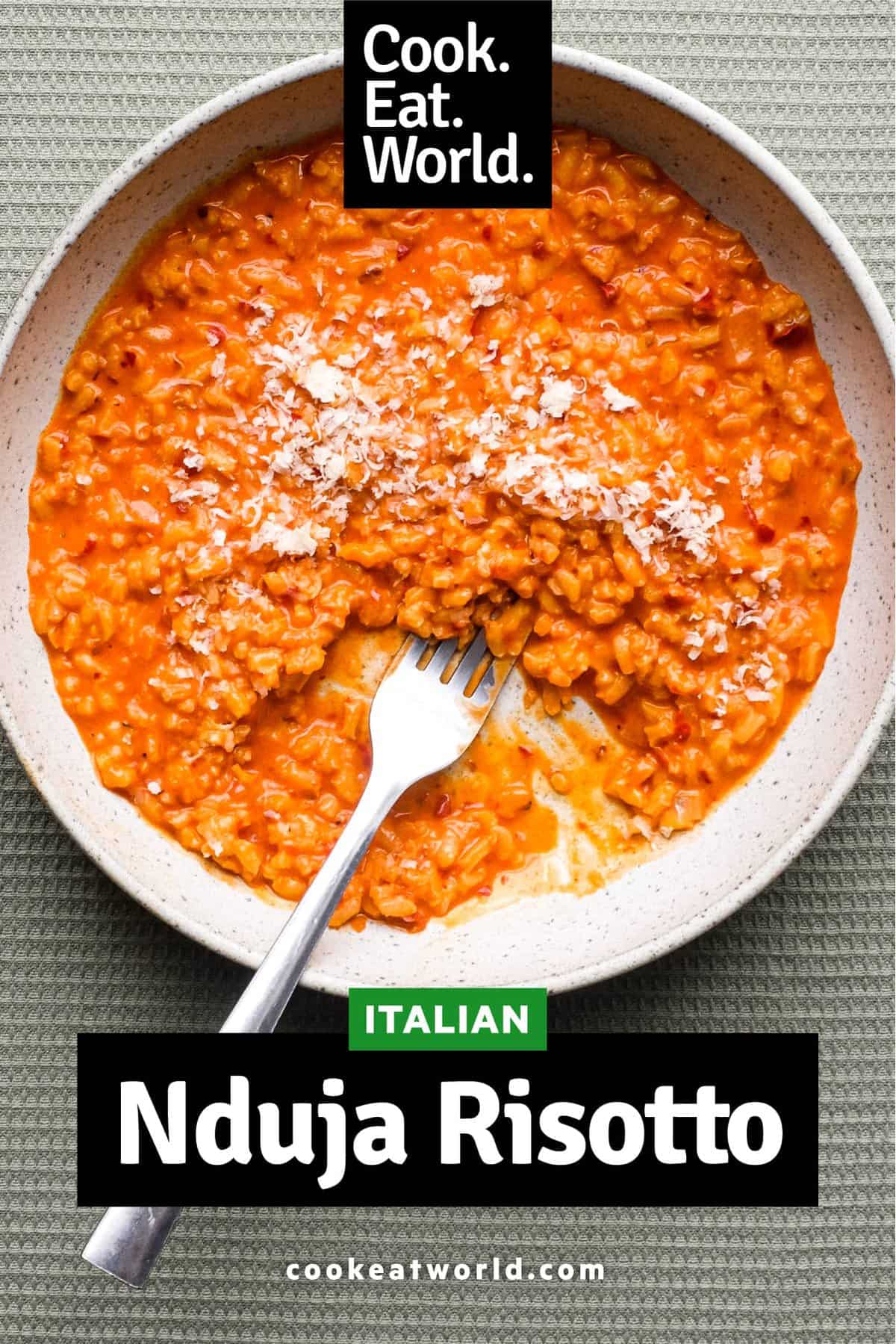 A bowl of Italian nduja risotto scattered with cheese. A fork sits alongside the bowl