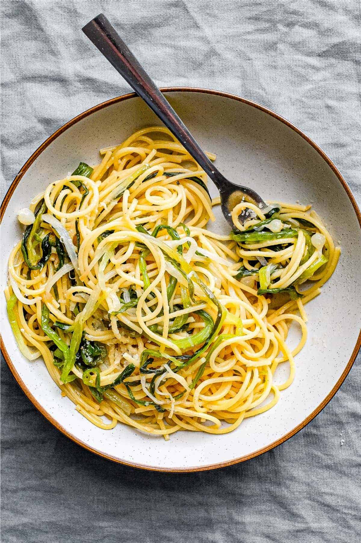 A bowl of spaghetti and wild onions with a fork