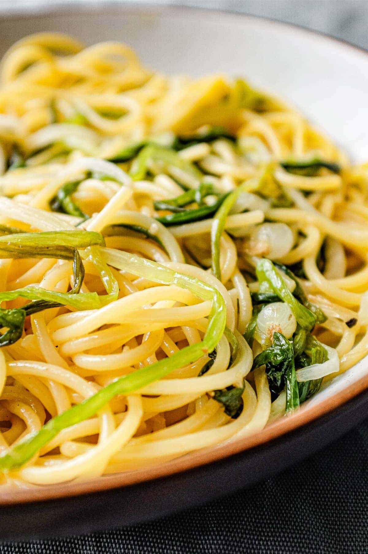 A bowl of spaghetti and wild onions with a fork