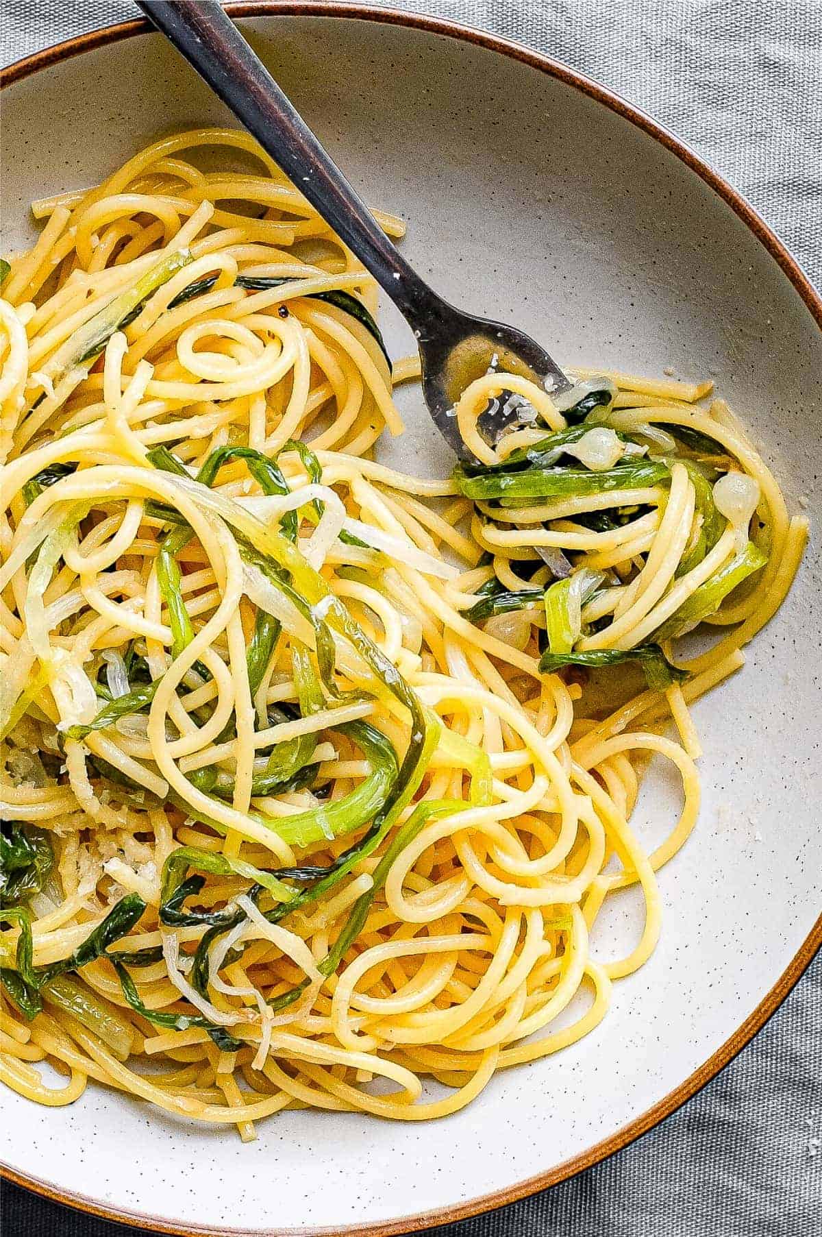 A bowl of spaghetti and wild onions with a fork