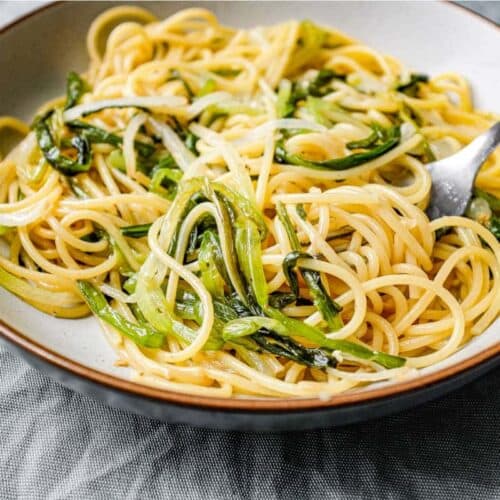 A bowl of spaghetti and wild onions with a fork