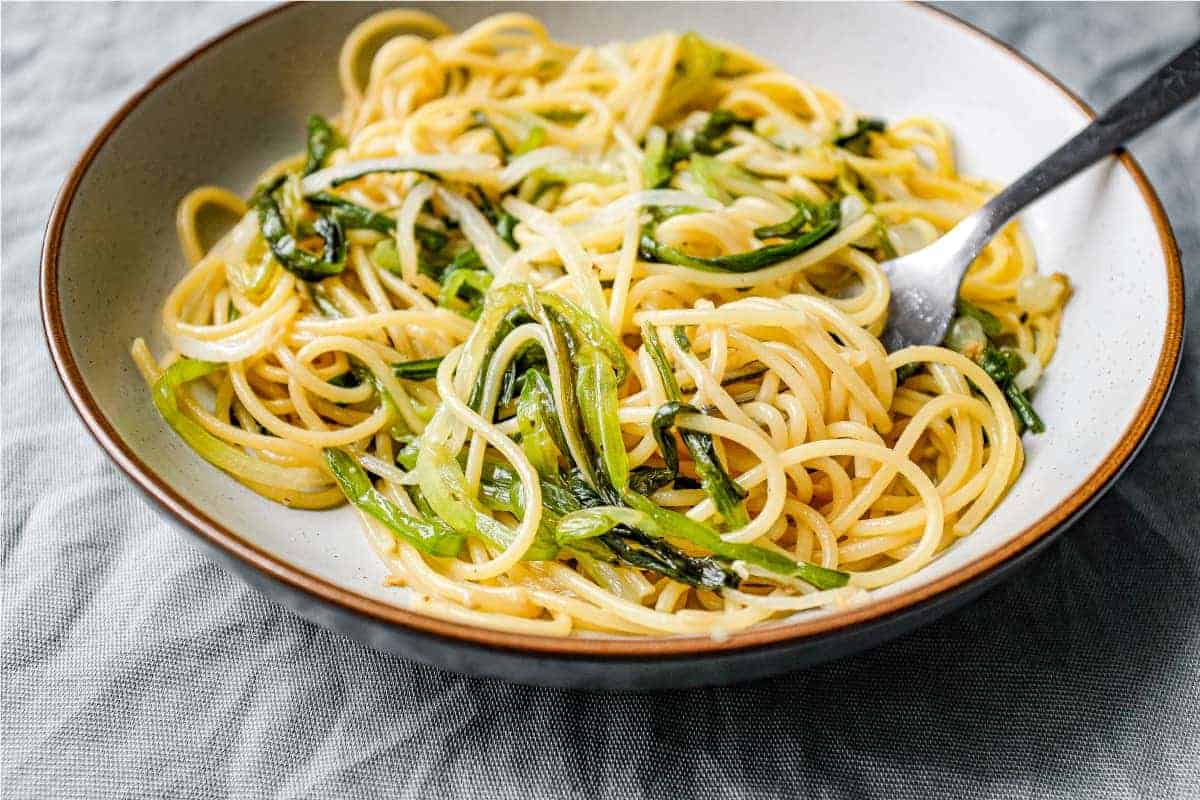 A bowl of spaghetti and wild onions with a fork