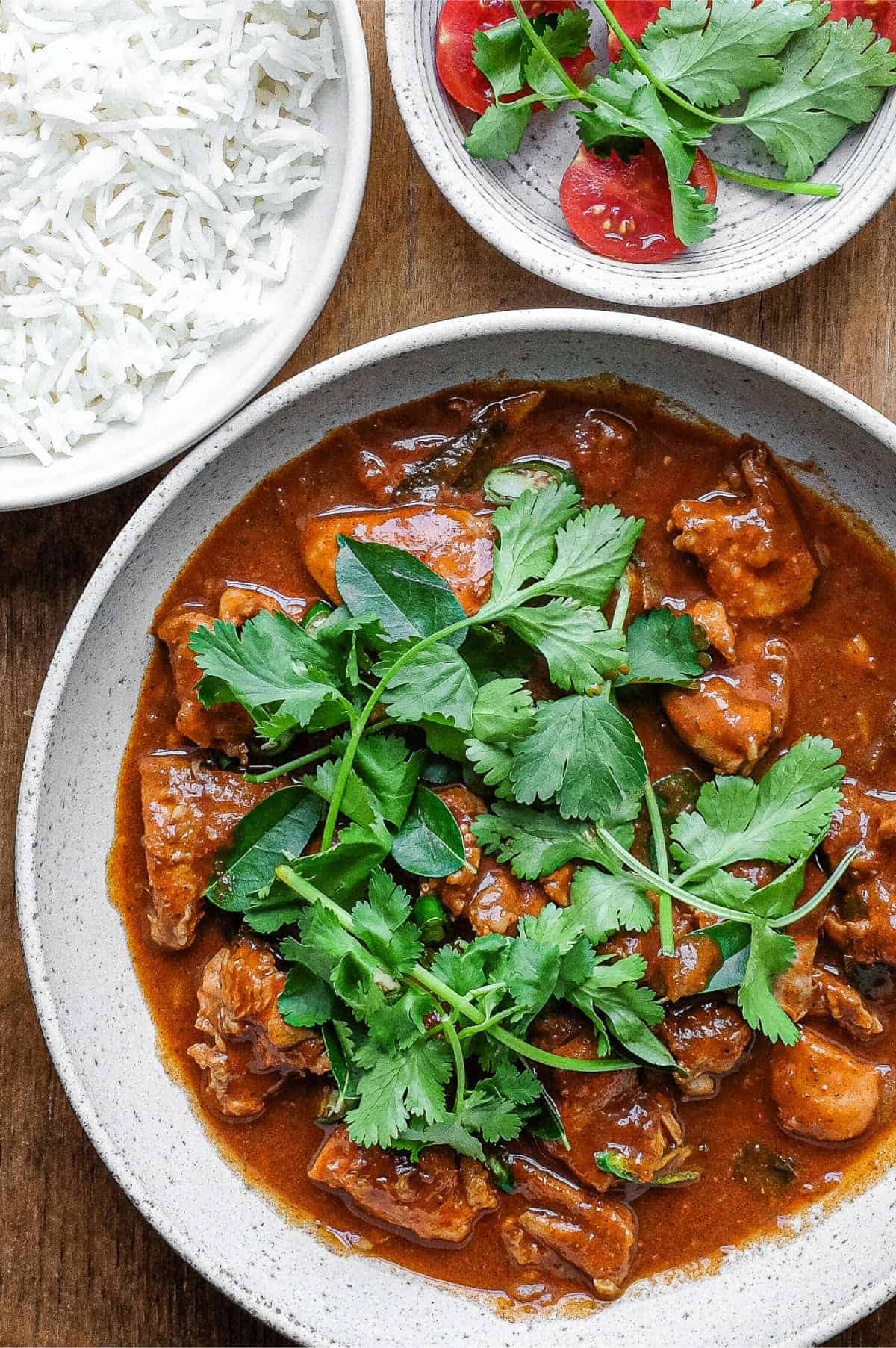 A bowl of Chicken Ceylon Curry scattered with fresh cilantro leaves