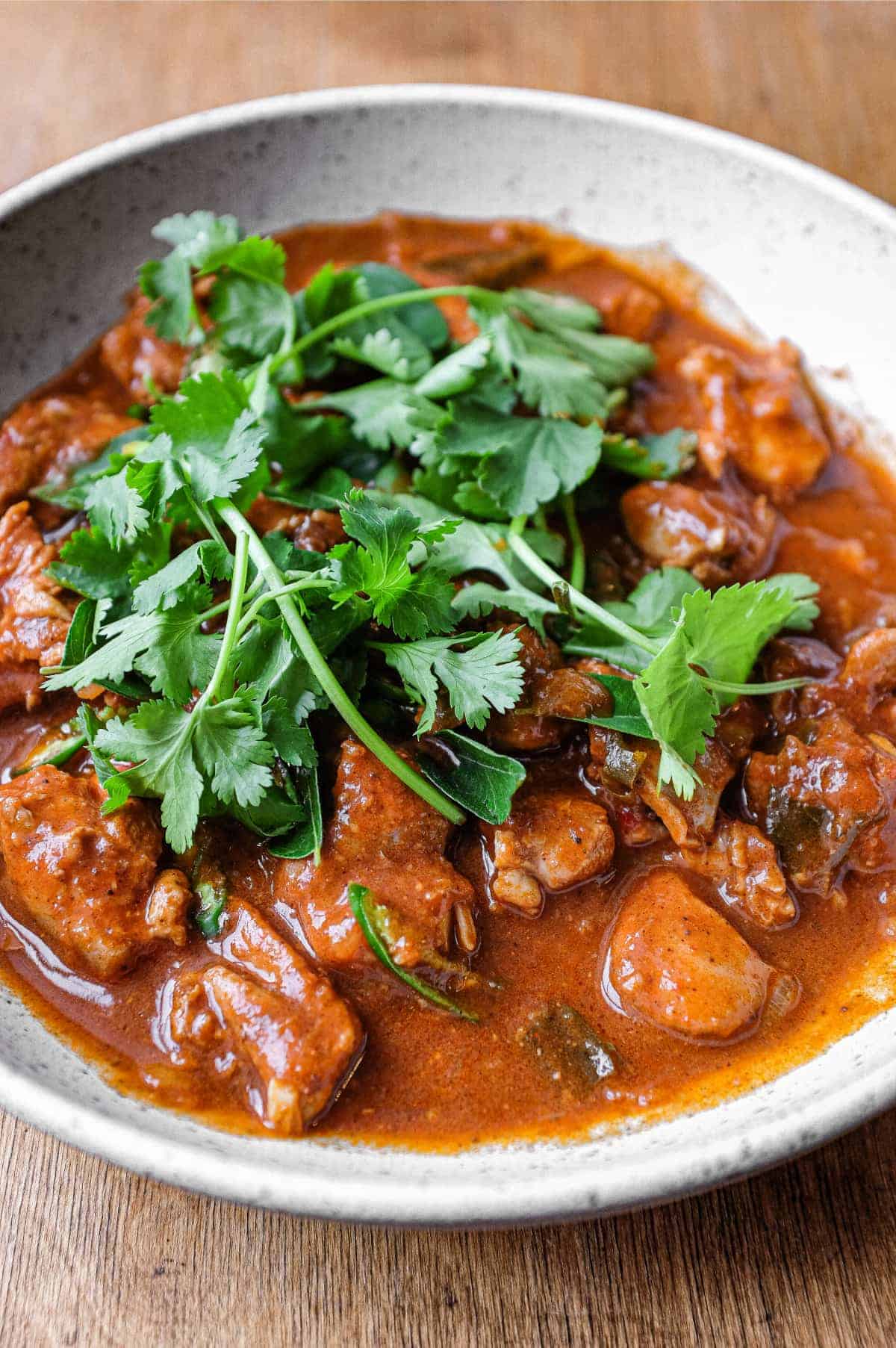 A bowl of Chicken Ceylon Curry scattered with fresh cilantro leaves