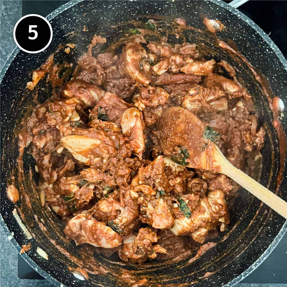 chicken being added to a pan for a Sri Lankan curry 