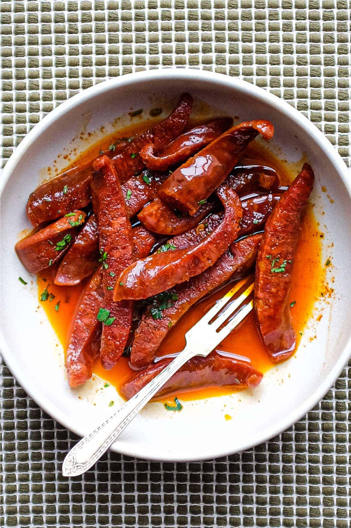 A small tapas bowl of Chorizo in a fino sherry sauce with a small tapas fork