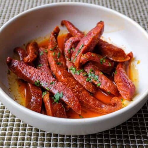 A small tapas bowl of Chorizo in a fino sherry sauce with a small tapas fork