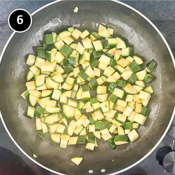 Diced zucchini frying in a pan
