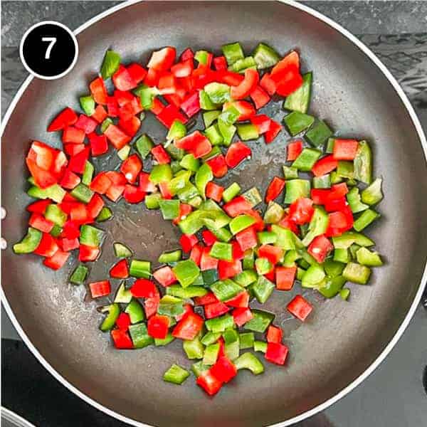 Diced red and green bell peppers frying in a pan