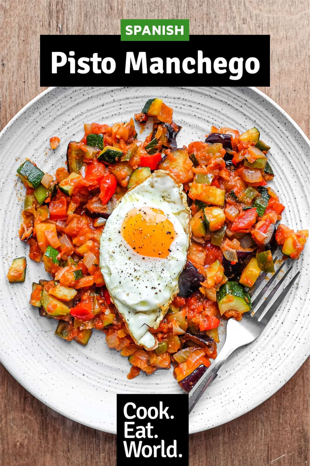 A plate of Spanish Pisto Manchego topped with a crisp fried egg. A fork sits alongside.