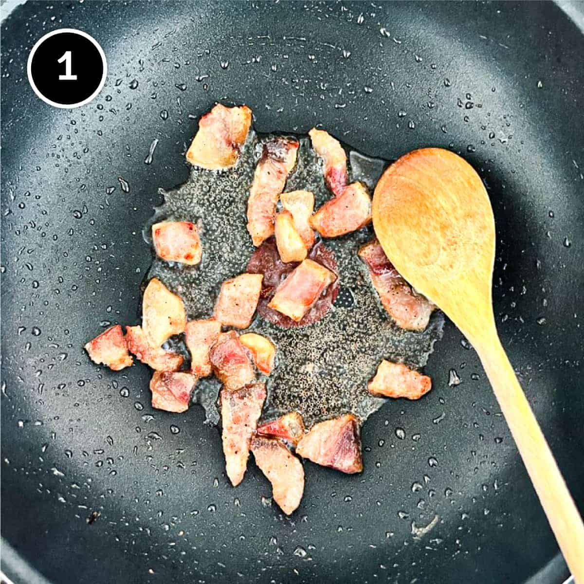 Guanciale bacon is fredde in a pan, rendering out its fat. A wooden spoon stirs.