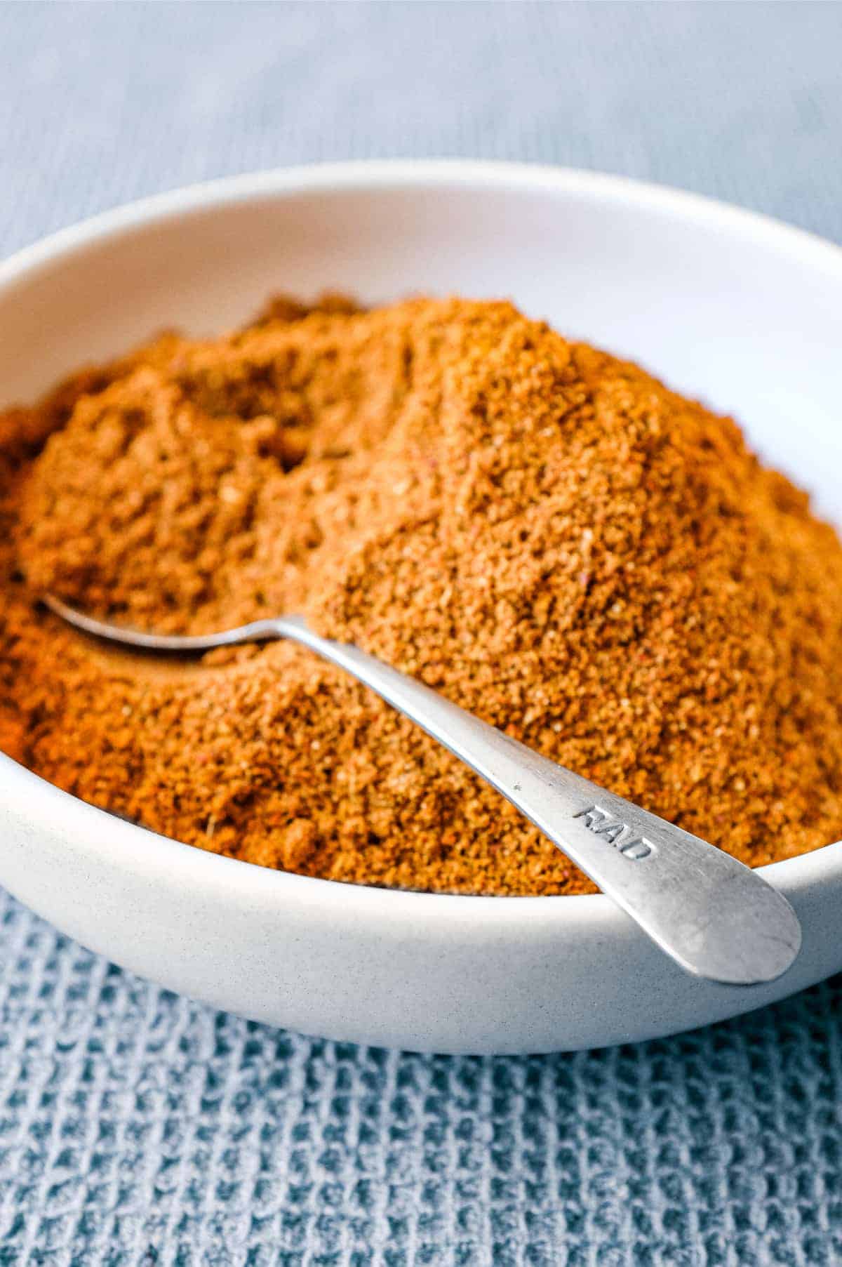 A small bowl of Sri Lankan curry powder with a spoon