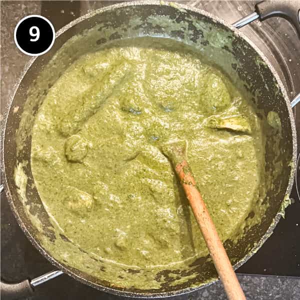 Spinach curry in a pan with a wooden spoon