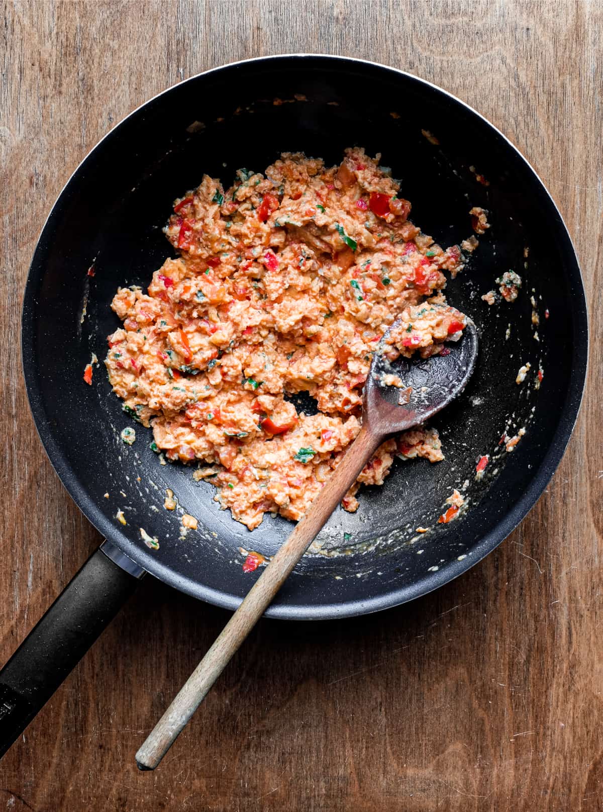 A pan of Greek strapatsada and a wooden spoon.