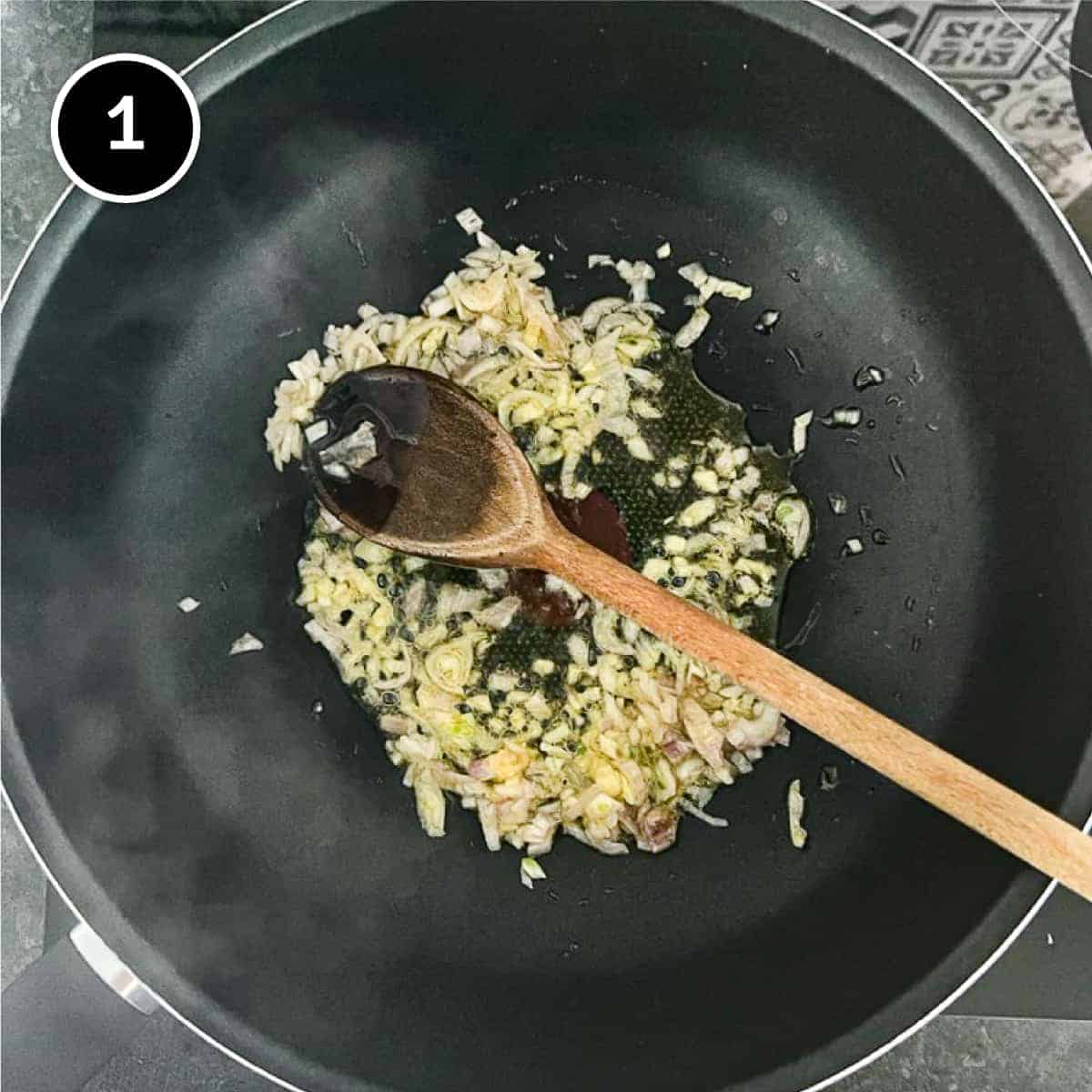 onion and garlic frying in a pan with a wooden spoon