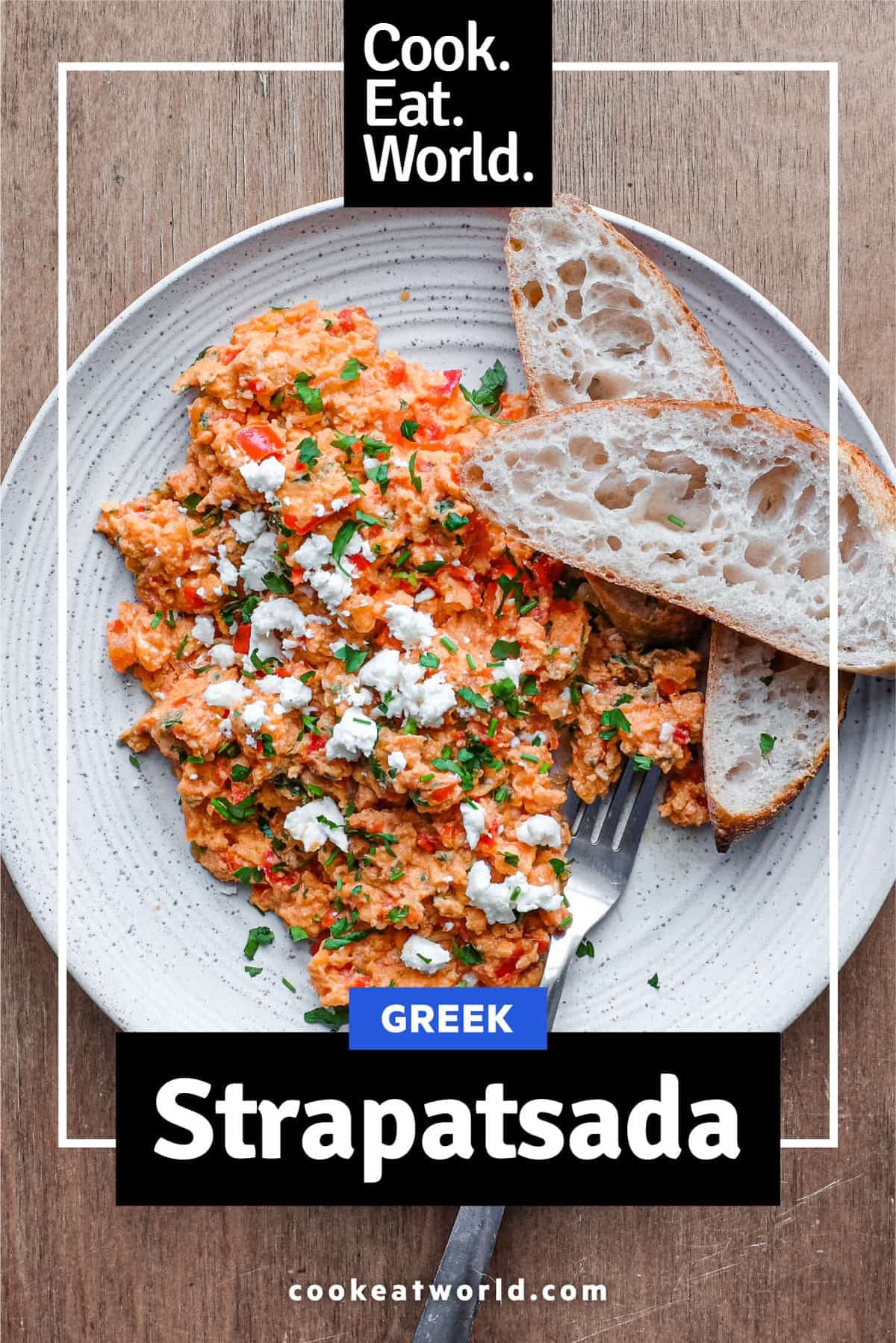 A plate of Greek Strapatsada scattered with feta cheese and parsley. Crusty bread and a fork sits alongside.