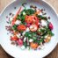 A bowl of Greek lentil salad featuring tomatoes, spinach, lentils, feta and red onion