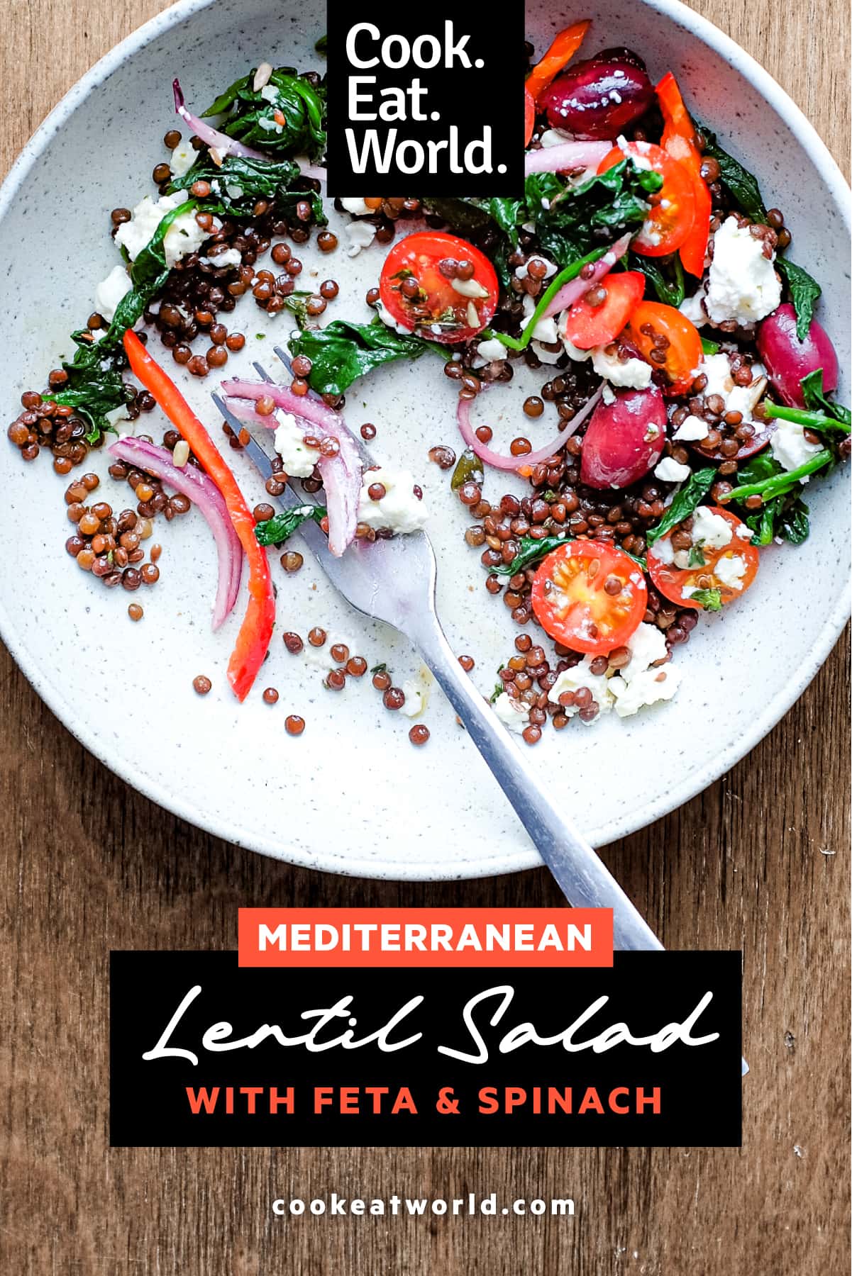 A bowl of Greek lentil salad featuring tomatoes, spinach, lentils, feta and red onion