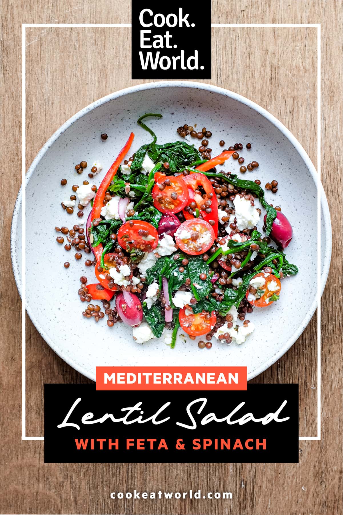 A bowl of Greek lentil salad featuring tomatoes, spinach, lentils, feta and red onion
