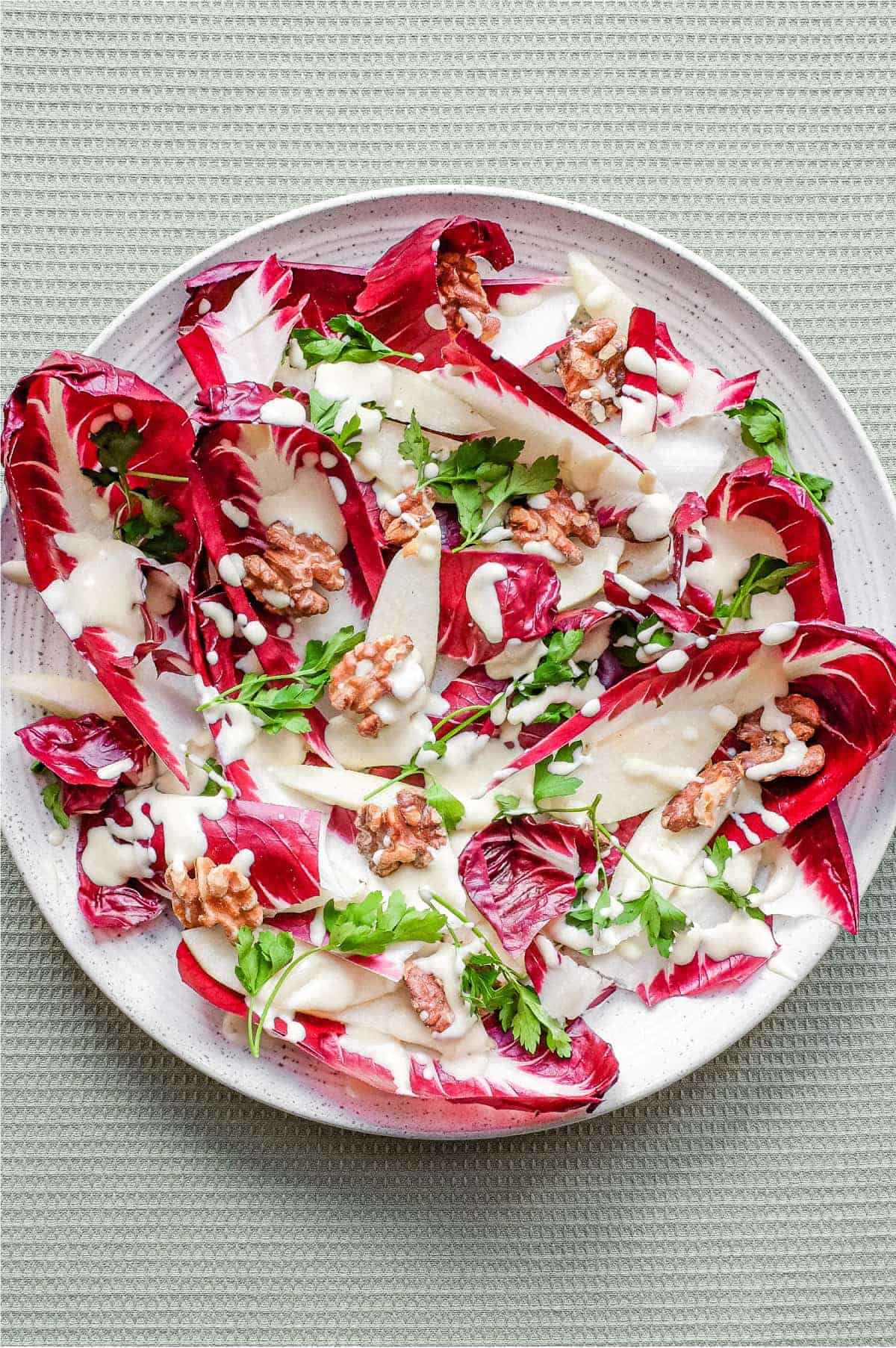 A platter of radicchio salad with pears, walnuts, parsley and a gorgonzola dressing