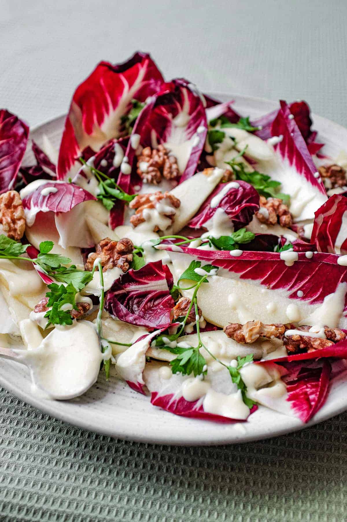 A platter of radicchio salad with pears, walnuts, parsley and a gorgonzola dressing