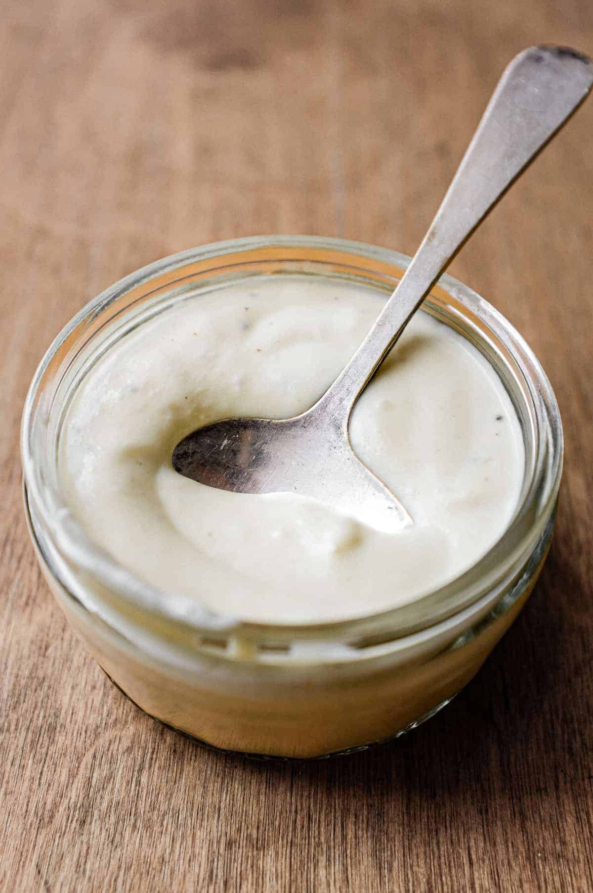 A small glass bowl of gorgonzola cheese dressing with a spoon.