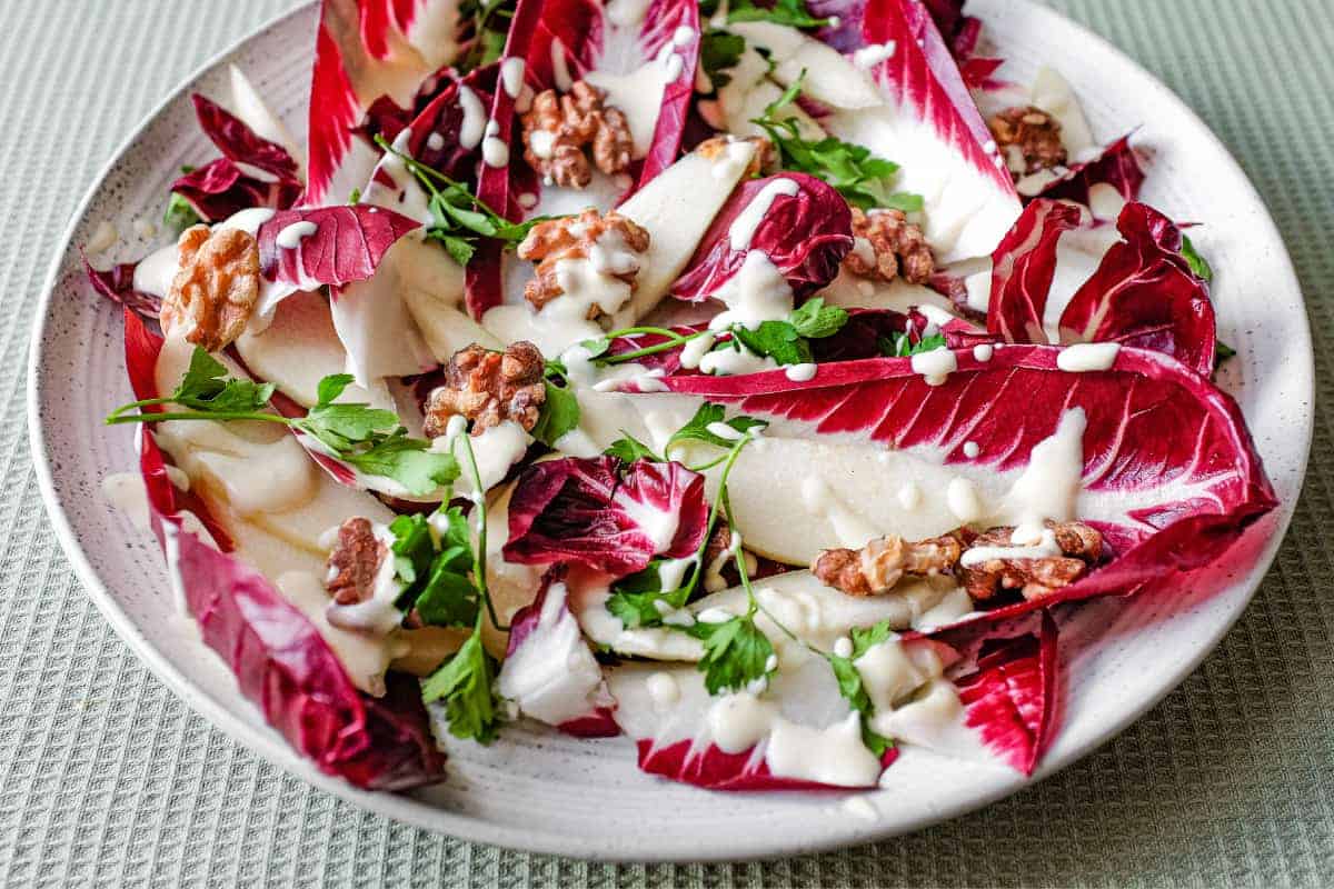 A platter of radicchio salad with pears, walnuts, parsley and a gorgonzola dressing
