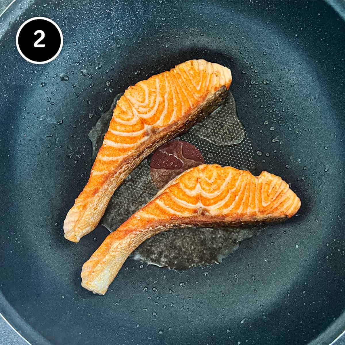 Salmon fillets being fried in a small frying pan