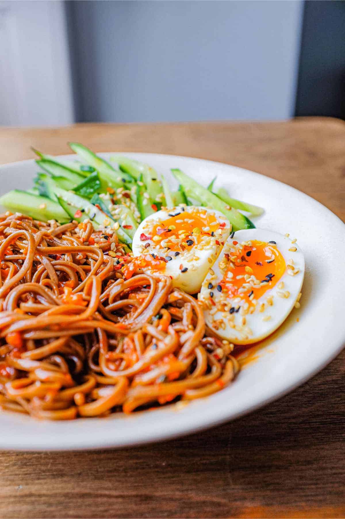 A bowl of Asian noodles called Bibim Guksu. Garnished with eggs and cucumber. 