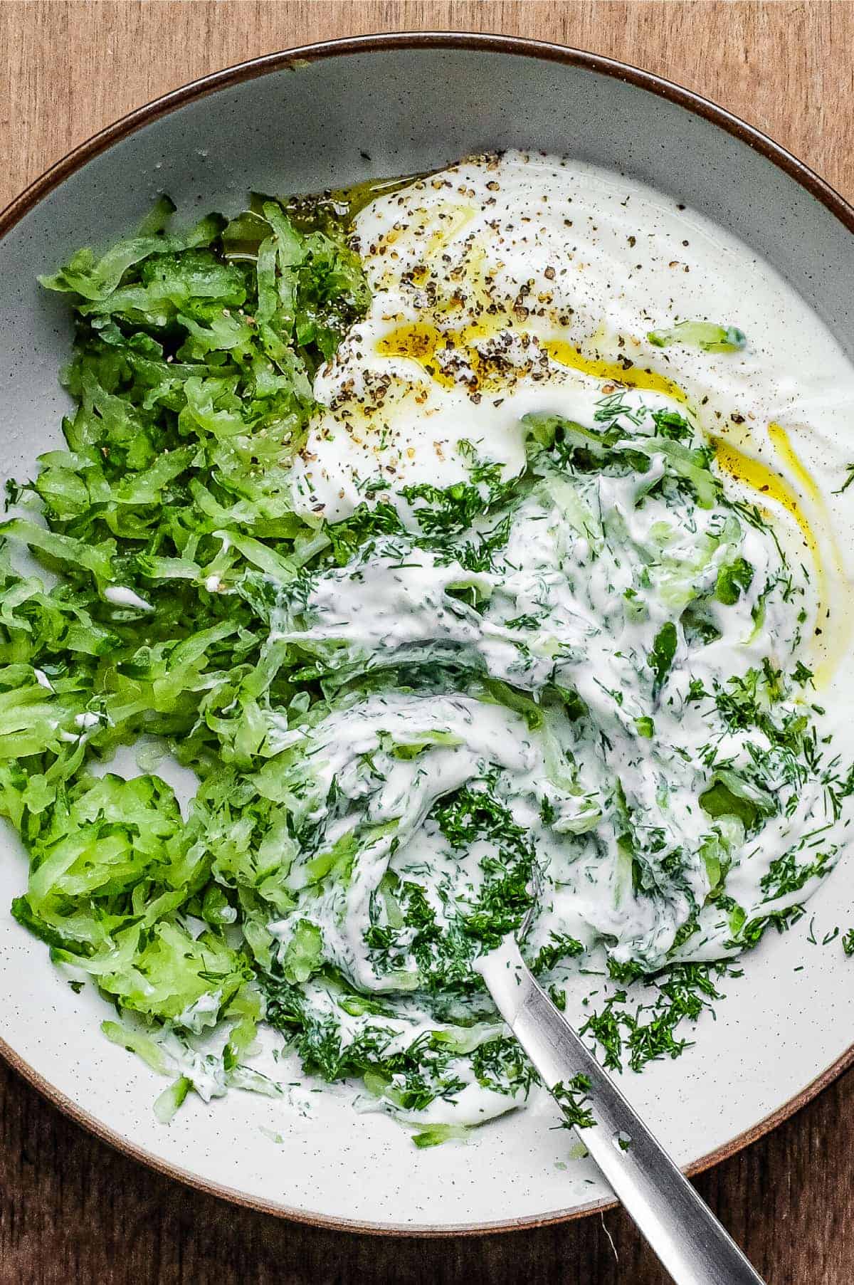 Mixing a bowl of Turkish Cacik - a yoghurt and cucumber meze or condiment