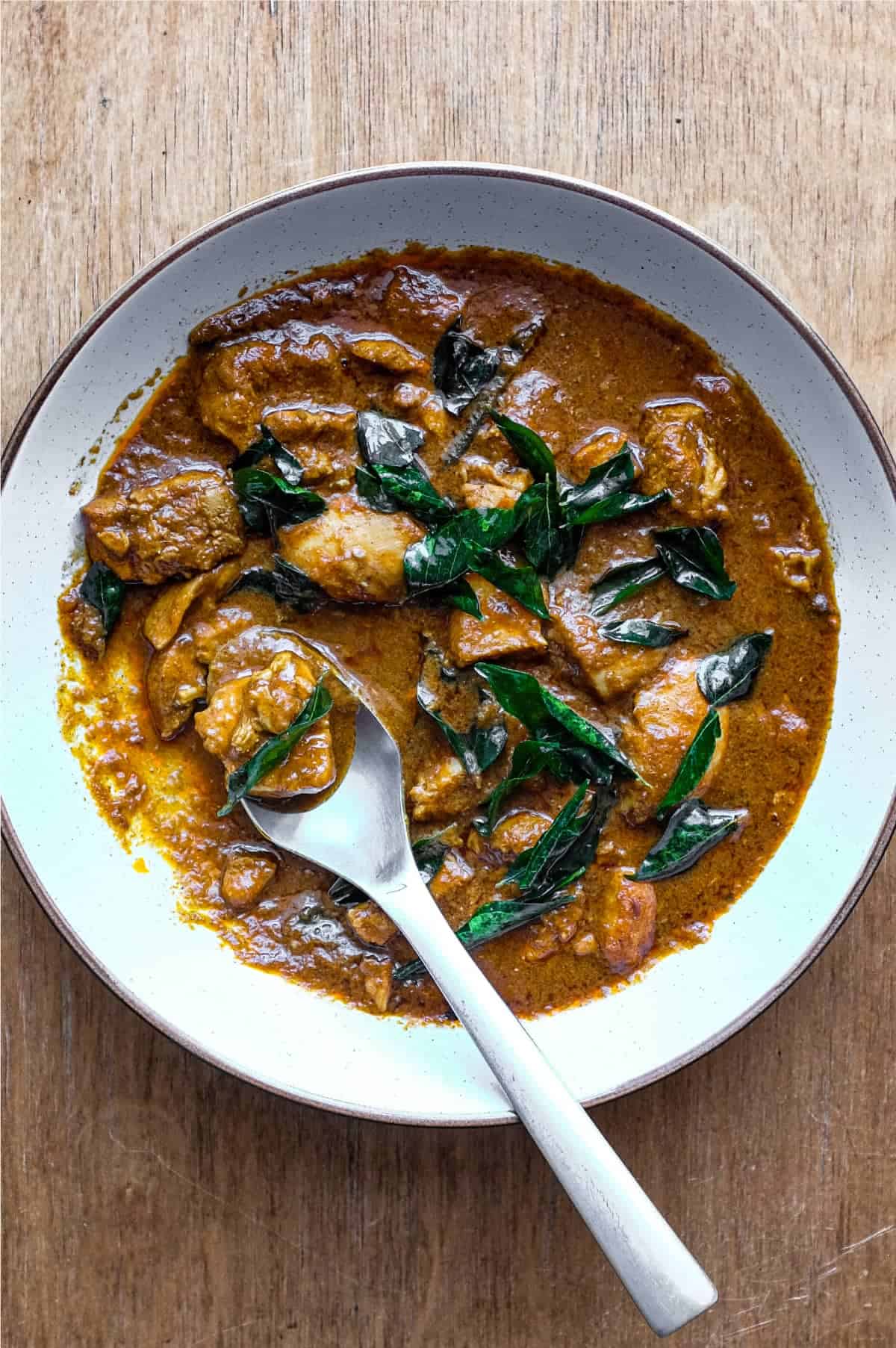 A bowl of Chicken Madras Curry scattered with fried curry leaves