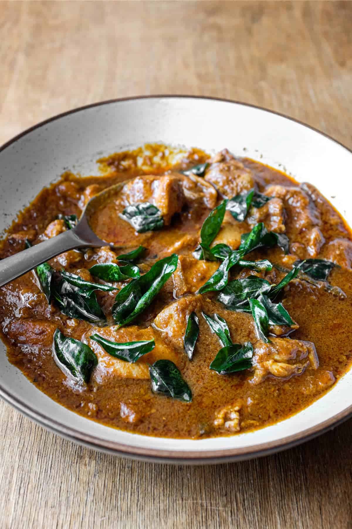 A bowl of Chicken Madras Curry scattered with fried curry leaves